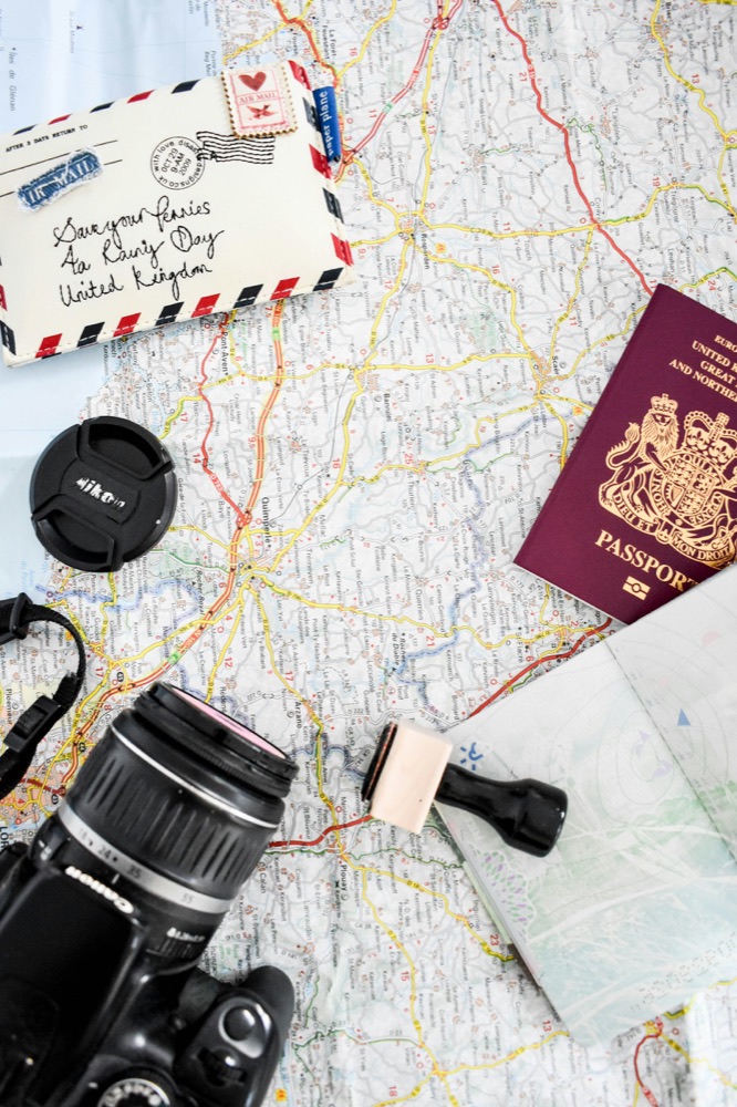 A paper map with a passport, a letter and a camera laid on top